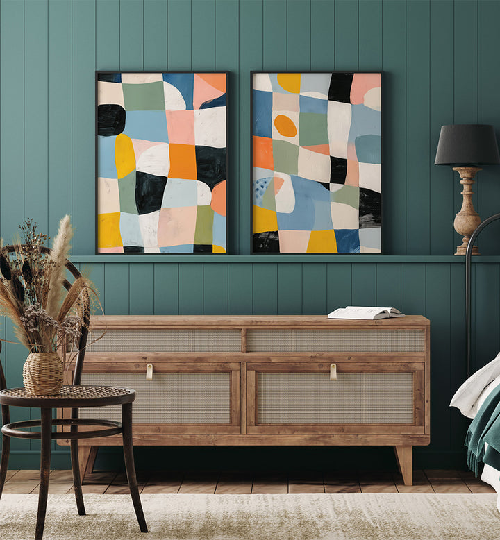 Two abstract art pieces on a green wall above a wooden console table.