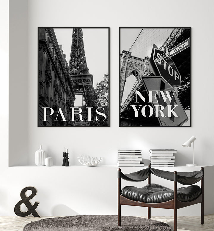 Two framed prints of the Eiffel Tower and a street sign in New York, displayed on a wall above a desk.