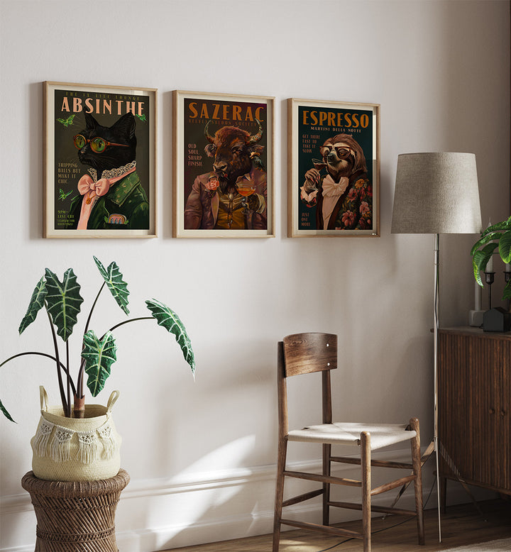 Three framed posters on a wall above a wooden chair with a plant and lamp in the foreground.