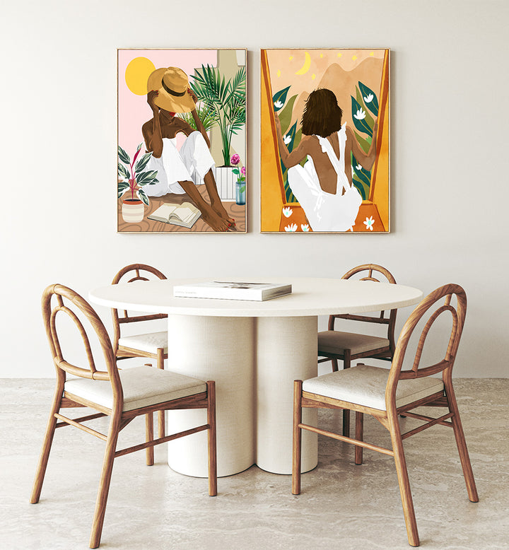 Dining room with a round table and chairs, featuring two framed artworks on the wall.