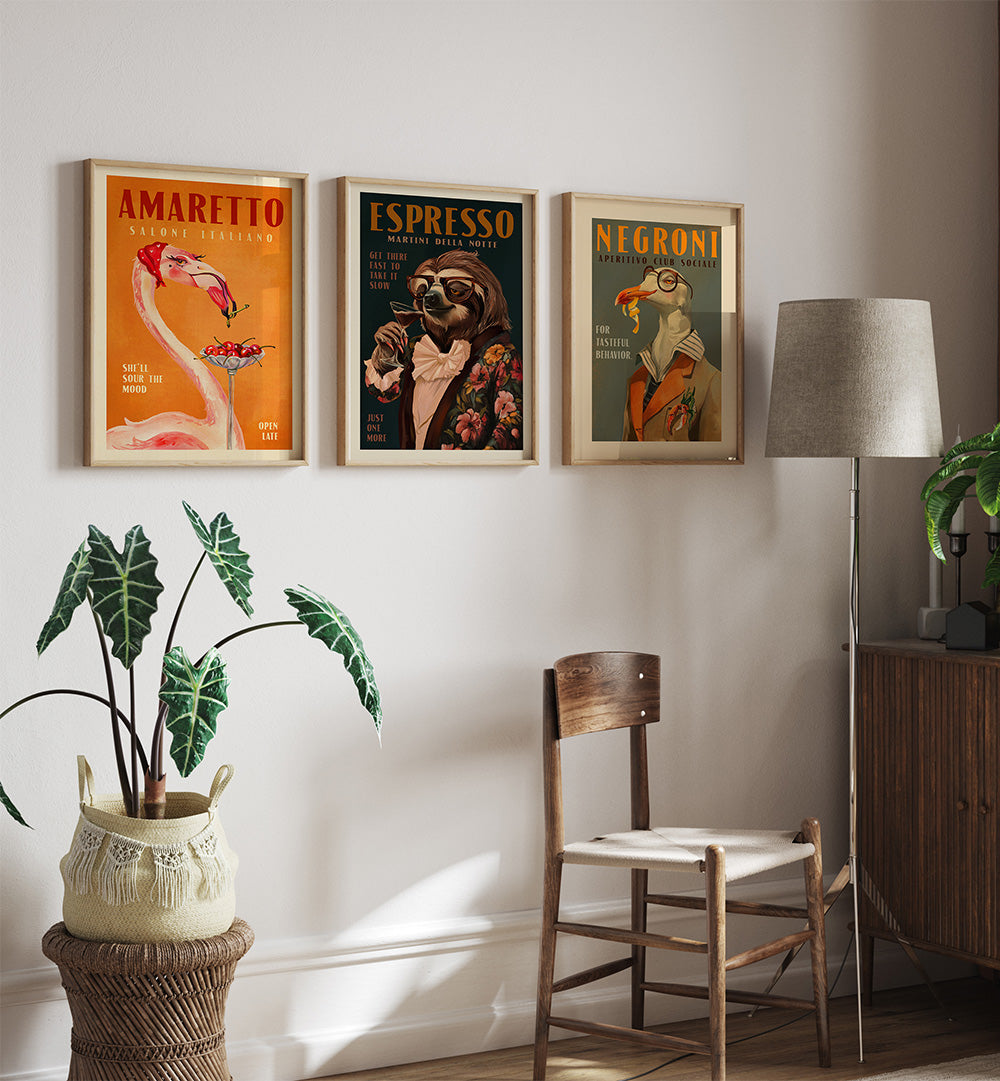 Three framed posters on a wall above a wooden chair with plants and a lamp.