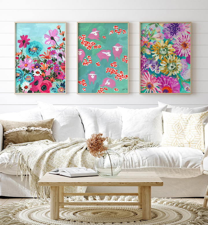 Colorful floral and animal prints on a wall above a white sofa with decorative pillows and a wooden coffee table.