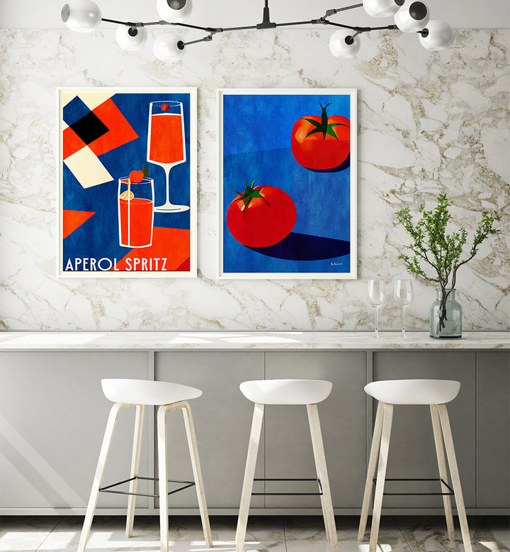 Two colorful posters on a wall above a kitchen counter with stools.