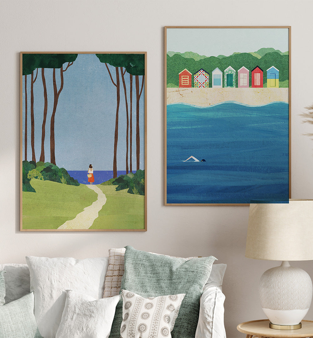 Two framed artworks on a wall above a sofa with decorative pillows.