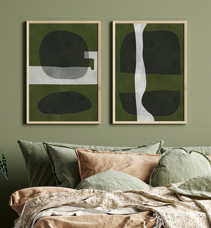 Two abstract art pieces on a green wall above a sofa with cushions.