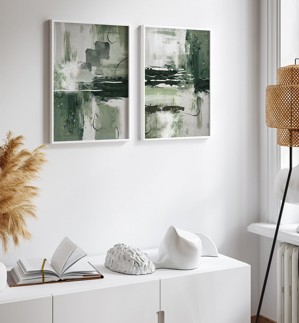 Two abstract paintings on a wall above a white cabinet with decorative items.