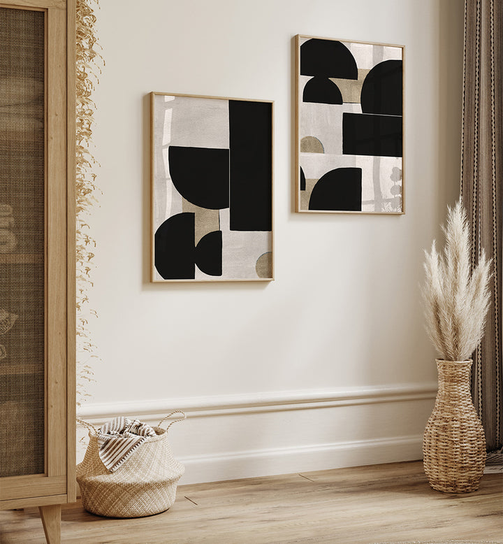 Two abstract art pieces on a wall with decorative baskets and a vase below.