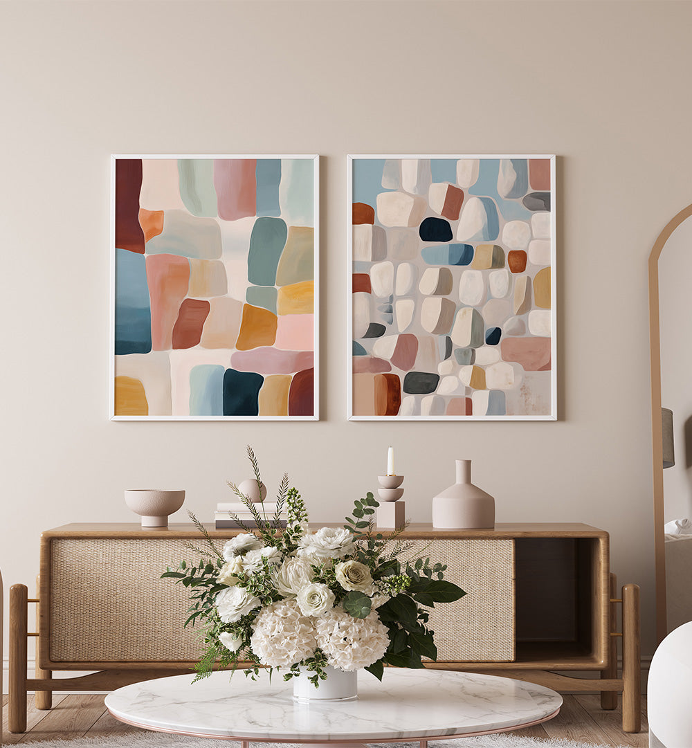 Two abstract art pieces on a wall above a wooden console table with decorative items.