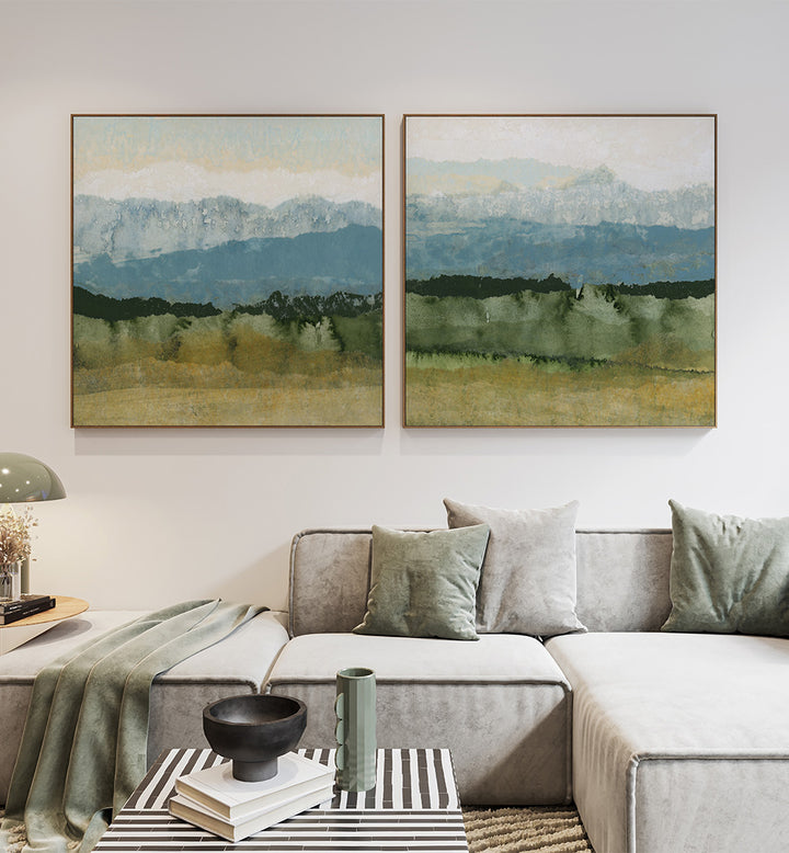 Living room with a gray sectional sofa, decorative pillows, and two framed landscape paintings on the wall.