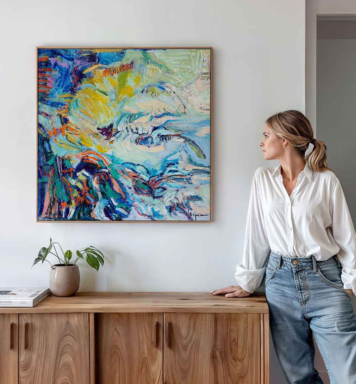 FLOWING HUES , ABSTRACT PAINTINGS vibrant blue and yellow abstract canvas above wooden console, woman admiring
