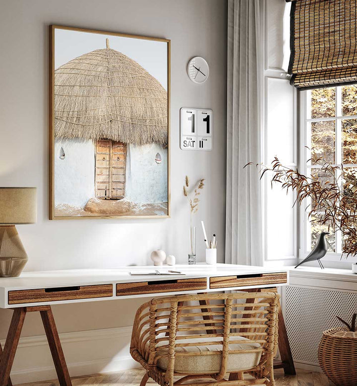 THATCHED HAVEN , INDIAN ART PAINTINGS framed rustic thatched hut art above desk in cozy neutral workspace
