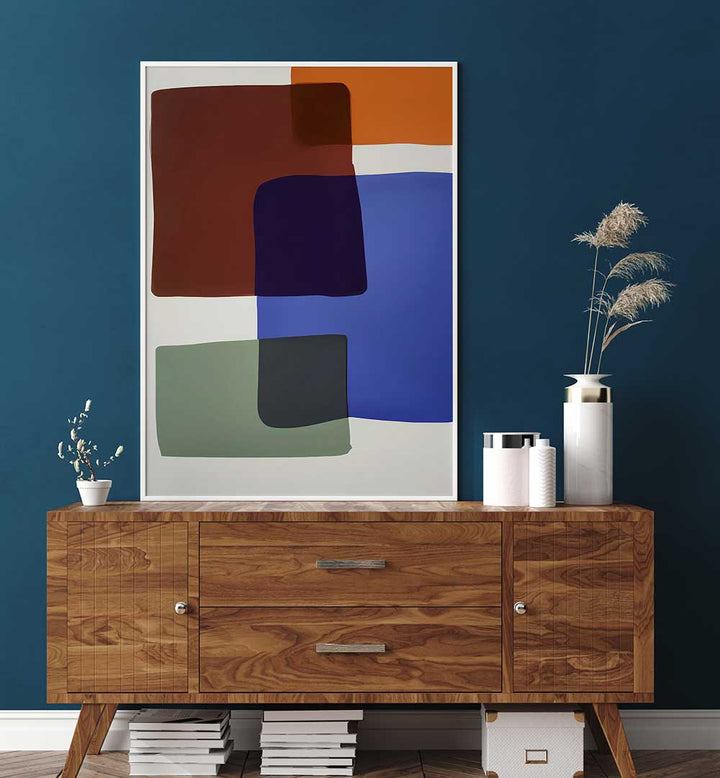 OUT OF THE BOX , ABSTRACT PAINTINGS featuring bold color blocks in blue, rust, green, and black on white backdrop above wooden sideboard