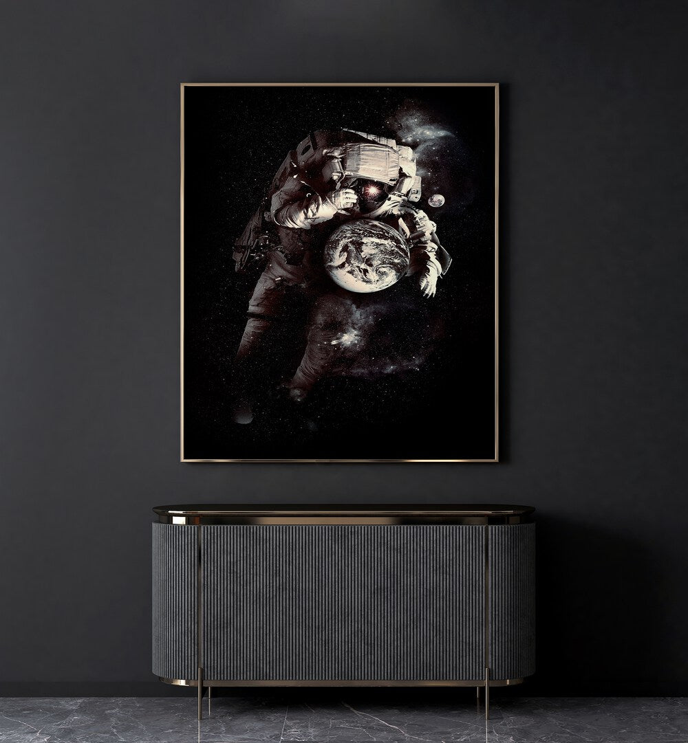 A Small World After All By Francis Minoza Astronaut & Nasa Paintings, Space Art Prints Artwork in Gold Plain Frame placed on a Dark Grey Colored Wall placed above a Console Table in the Drawing Room
