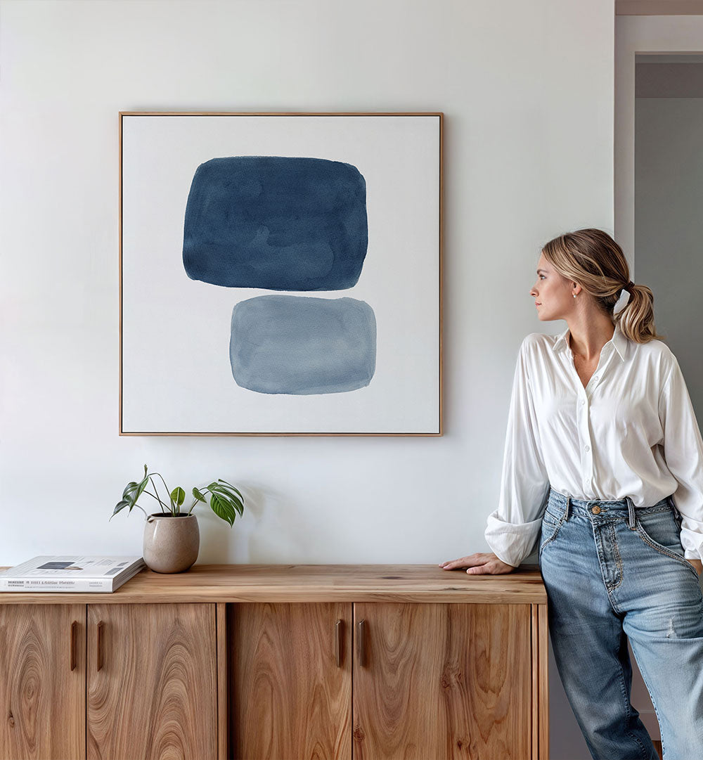 Stylish woman admires AFFINITY, GEOMETRIC ART PRINTS on wall, enhancing her modern living space with abstract beauty.