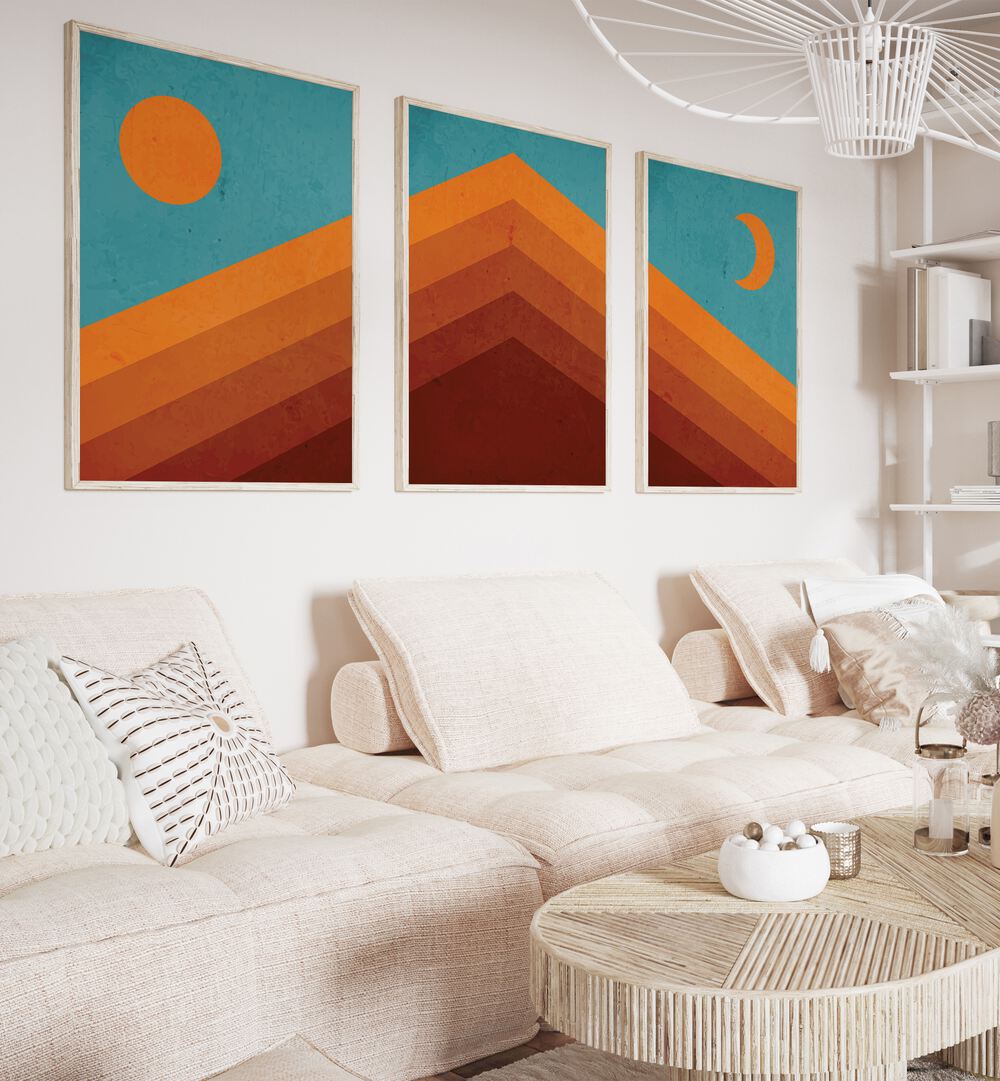 Abstract Mountain Sunrise Set Of 3 Paintings in White Plain Frame placed on a wall living room wall behind a sofa