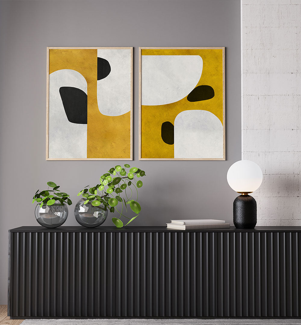 Two abstract art pieces on a gray wall above a black console table with decorative items.