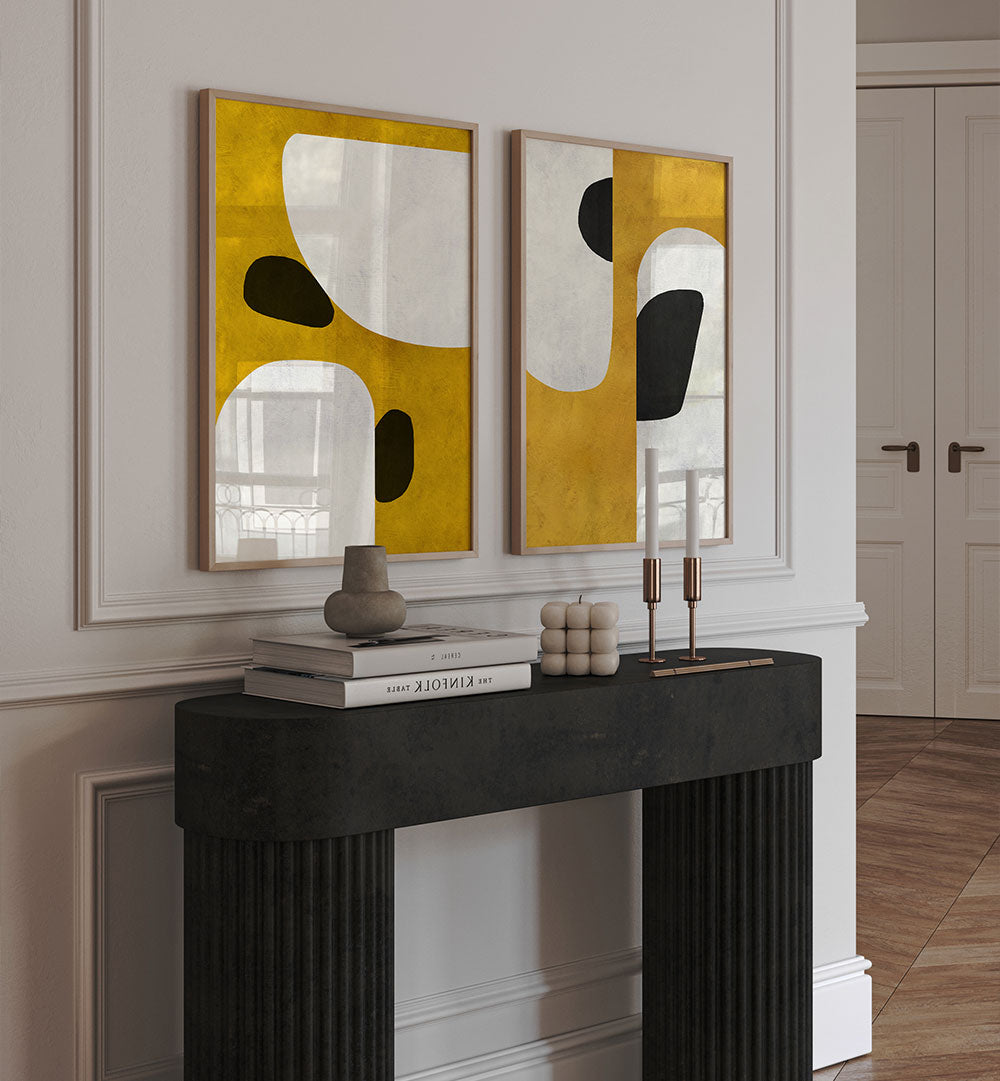 Two abstract art pieces on a wall above a fireplace with decorative items.