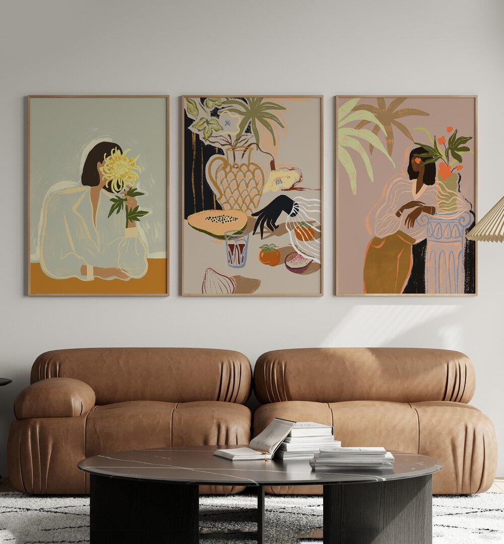 Arty Guava Artworks Set Set Of 3 Paintings in Oak Wood Plain Frame placed on a white wall behind a brown sofa