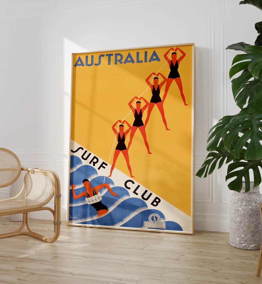 Australia Surf Club  Retro Travel Posters in Oak Wood Plain Frame placed on a floor beside a chair and plant