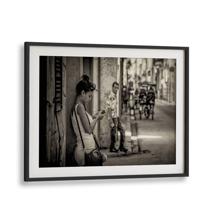 A woman engaged with her phone on a La Habana street, featured in our LA HABANA STREET, PHOTOGRAPHY PRINTS collection.