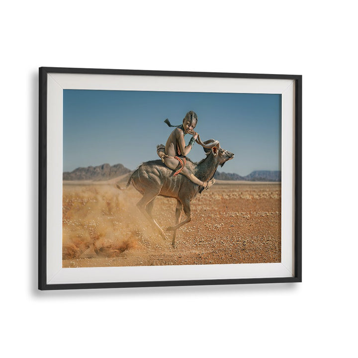 A child rides an antelope in a desert scene, showcasing the beauty of wildlife in EASY RIDER, PHOTOGRAPHY PRINTS.