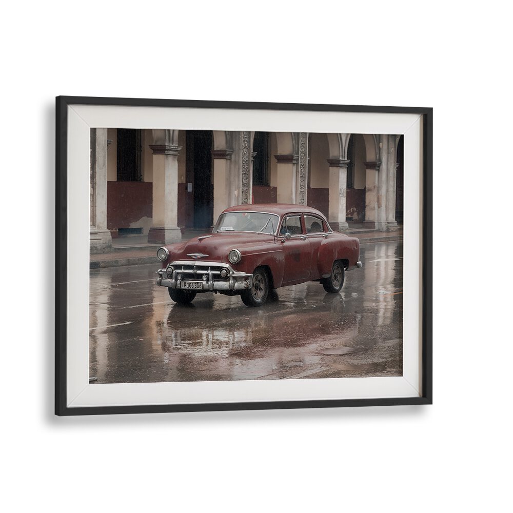 Red vintage car parked on a rain-soaked street, showcasing the essence of DRIVING BY RAIN, PHOTOGRAPHY PRINTS.