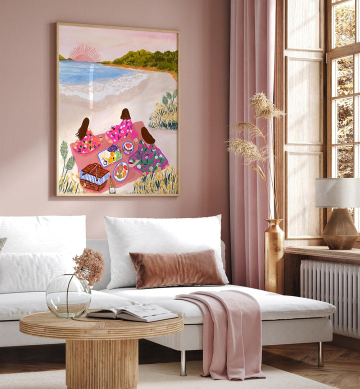 Beach Picnic By Sarah Gesek Coastal Wall Art Prints in Oak Wood Plain Frame placed on a living room wall beside a window and behind a sofa