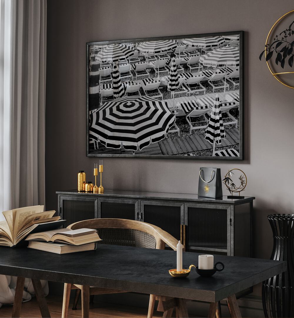 Black and White Beach Umbrellas II By Grace Digital Art Co Beach Prints in Black Plain Frame placed on a wall behind a table 