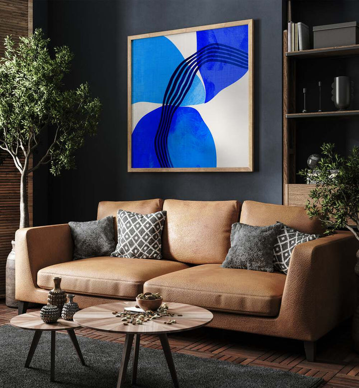 Blue Abstract Kopie II By Ana Rut Bre Abstract Art Abstract Paintings in Oak Wood Plain Frame placed on a Dark Grey Colored Wall near a Brown Sofa in the Living Room