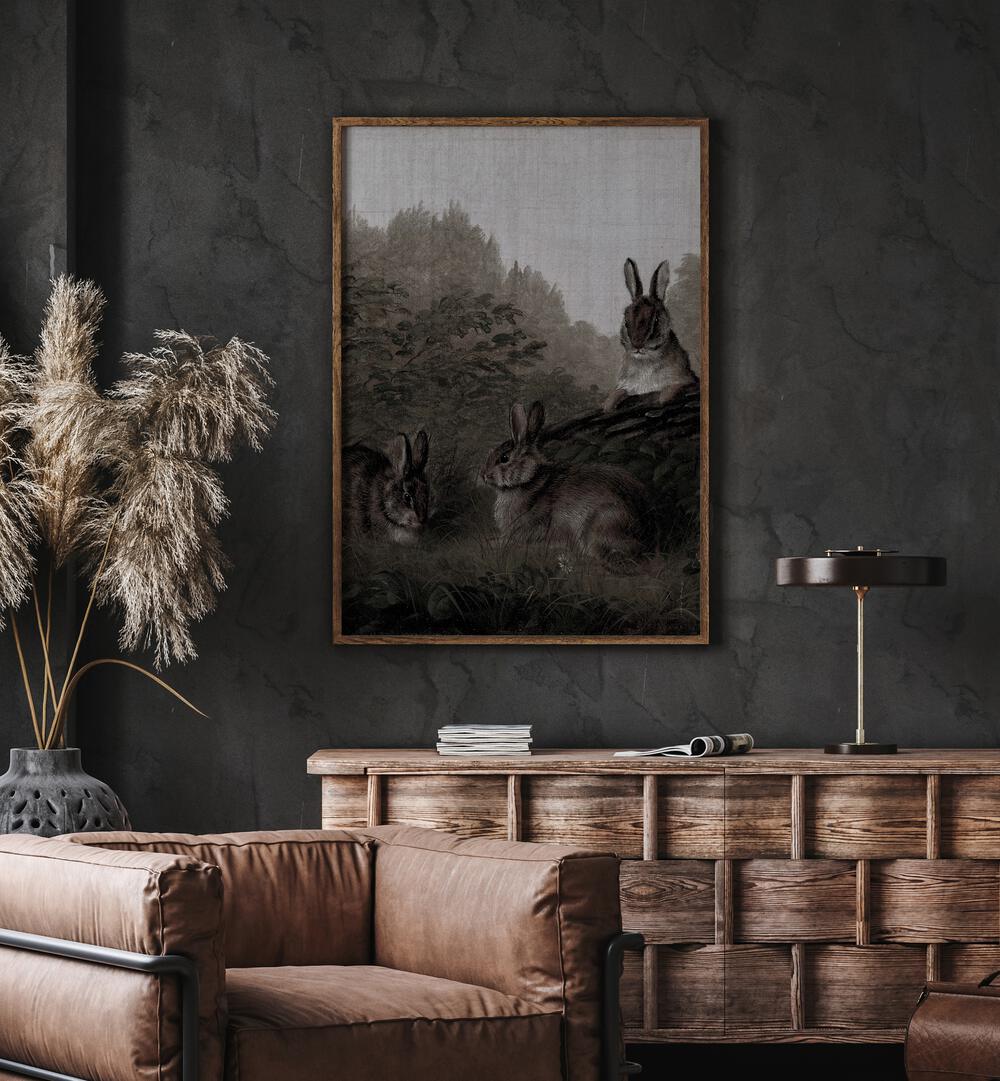 Bunny Dreams Whimsical Whiskers And Fluffy Tails Gothic Art Prints in Oak Wood Plain Frame hanging on wall above brown chair beside plant.