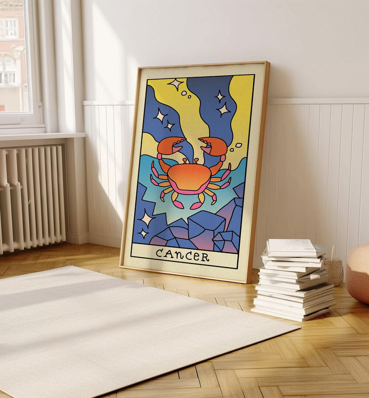 Cancer Zodiac & Tarot Art Painting Artwork in plain oakwood frame on a wooden floor beside a stack of books