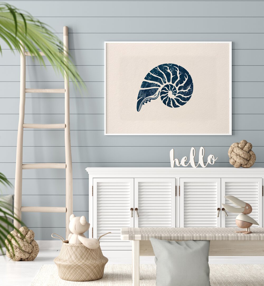 Cerulean Conch V Beach Prints Coastal Wall Art in White Plain Frame placed on a wall behind a white console table and a ladder