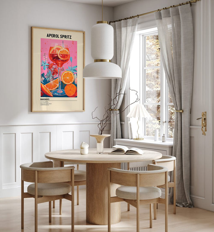 Colourful Aperol Spritz Cafe Art Prints Cafe Posters in Oak Wood Plain Frame placed on a wall in a dining room area beside a window and behind a dining table