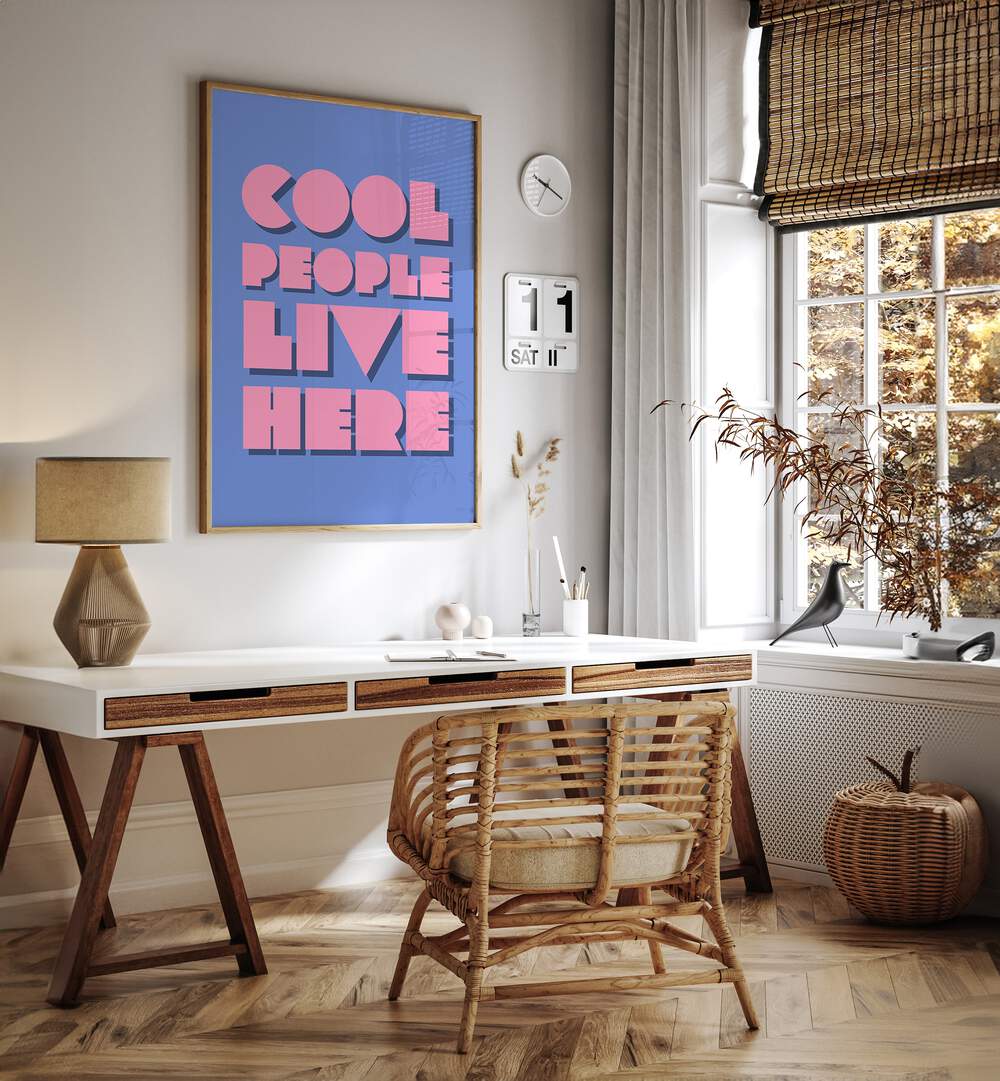 Cool People Live Here by Athene Fritsch Quotes and Typography Posters in Oak Wood Plain Frame placed on a wall behind a table and beside a window