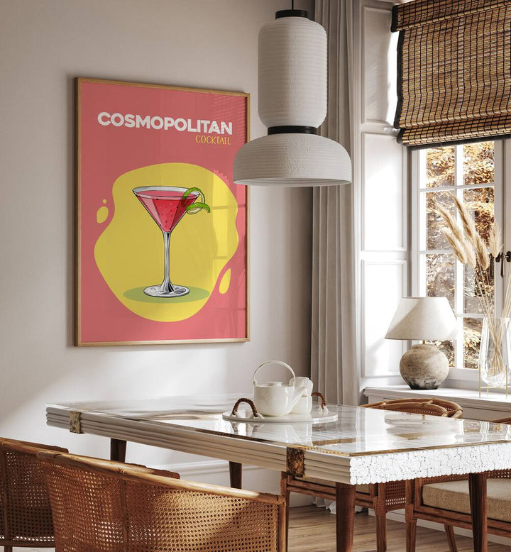 Cosmopolitan Cocktail I Cafe Art Prints Cafe Posters in Oak Wood Plain Frame placed on a wall in a dining room area beside a window and behind a dining table