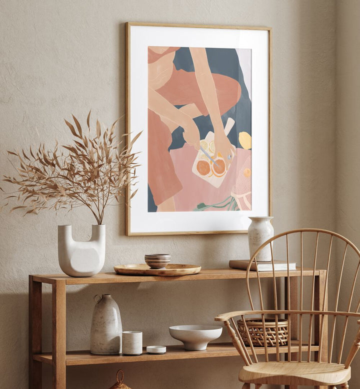 Cutting Grapefruits By Ivy Green Women Illustration Paintings in Oak Wood Frame With Mount on beige wall placed above a table