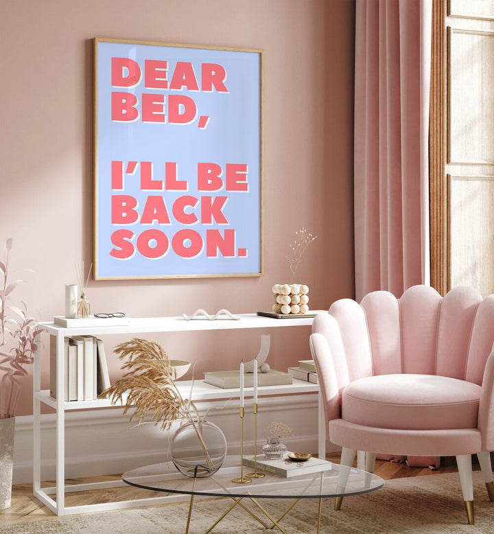 Dear Bed by Athene Fritsch Quotes and Typography Posters in Oak Wood Plain Frame placed on a pink wall beside a window and behind a table