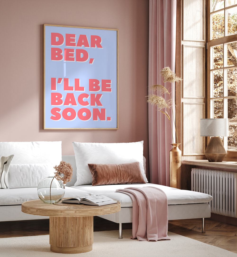 Dear Bed by Athene Fritsch Quotes and Typography Posters in Oak Wood Plain Frame placed on a pink wall beside a window and behind a sofa for living room