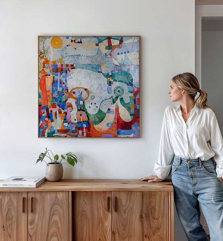 Framed DISTANT VILLAGE , ABSTRACT PAINTINGS hung over wooden console, woman gazing at bright layered colors