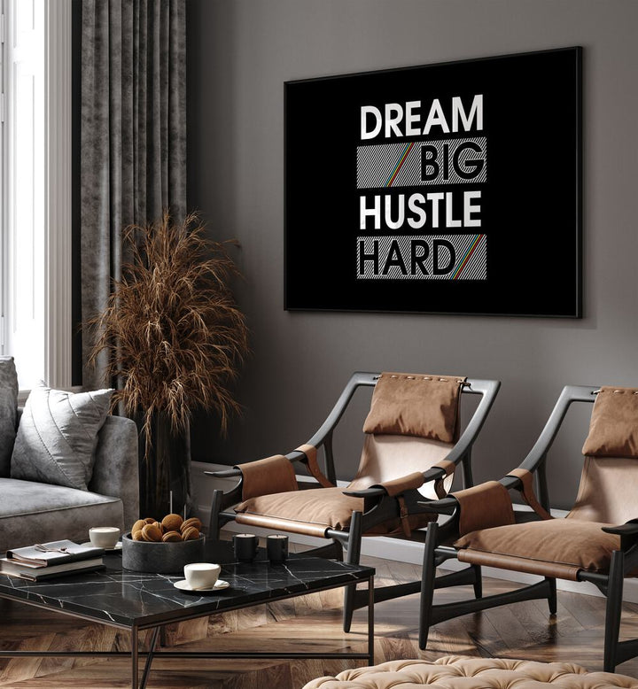 Dream Big Hustle Hard Quotes and Typography Posters in Black Plain Frame placed on a living room wall beside chairs