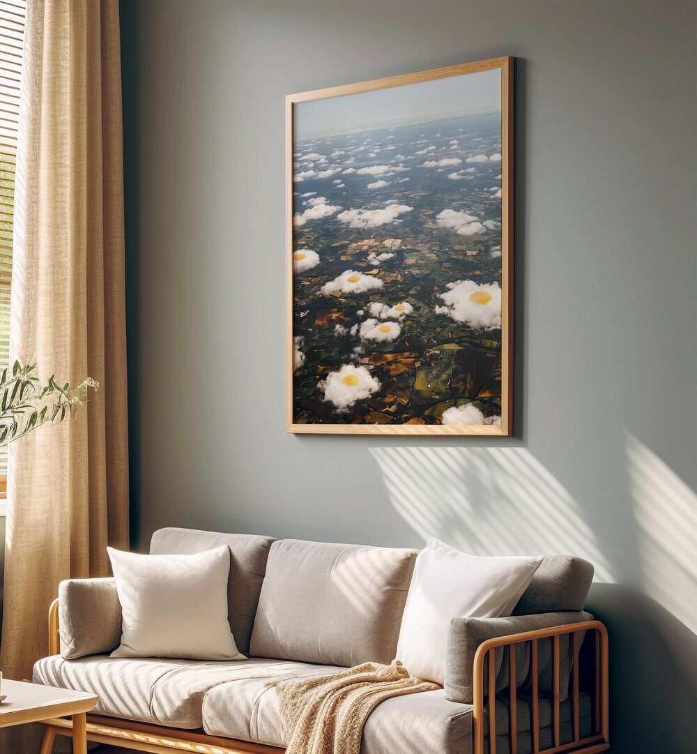 Eggy Clouds Surreal Art Painting Artwork in plain oakwood frame behind a sofa beside a window 