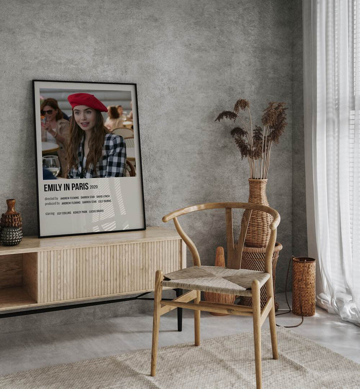 Emily In Paris 2020 ii Movie Posters in Black Plain Frame placed on a table beside oakwood chair