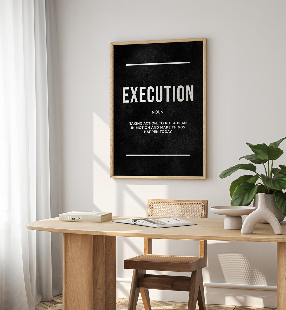 Execution II Quotes And Typography Posters in Oak Wood Plain Frame placed on a White Colored Wall near a Study Table in a Workspace in the Drawing Room