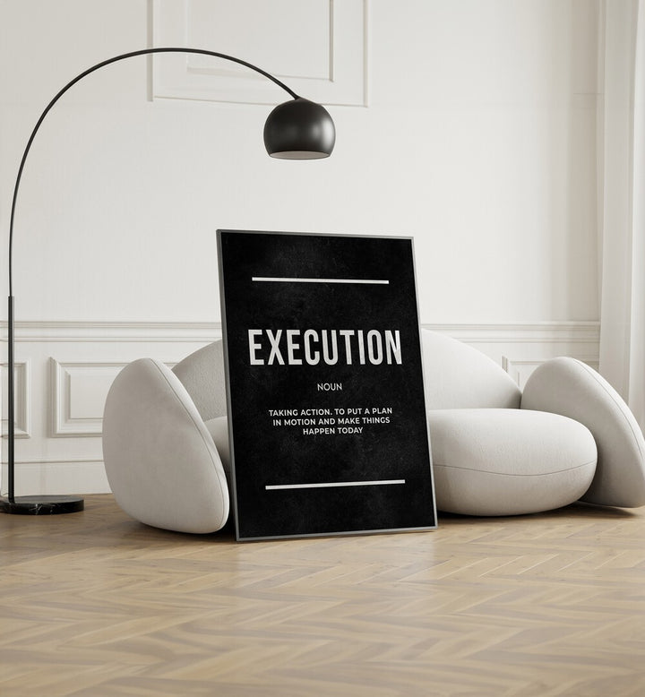 Execution II Quotes And Typography Posters in Black Plain Frame placed on the floor near a White Sofa in the Living Room