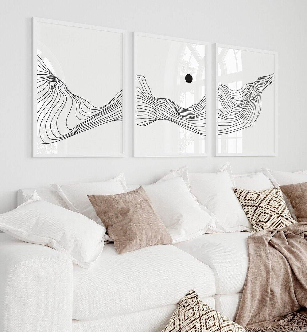 Fluidic Dunes Set Set Of 3 Paintings in White Plain Frame placed on a living room wall behind a white sofa