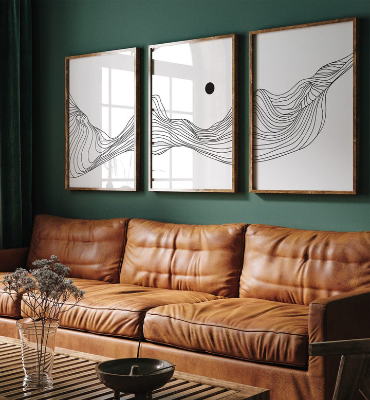 Fluidic Dunes Set Set Of 3 Paintings in Dark Wood Plain Frame placed on a living room wall behind a leather sofa