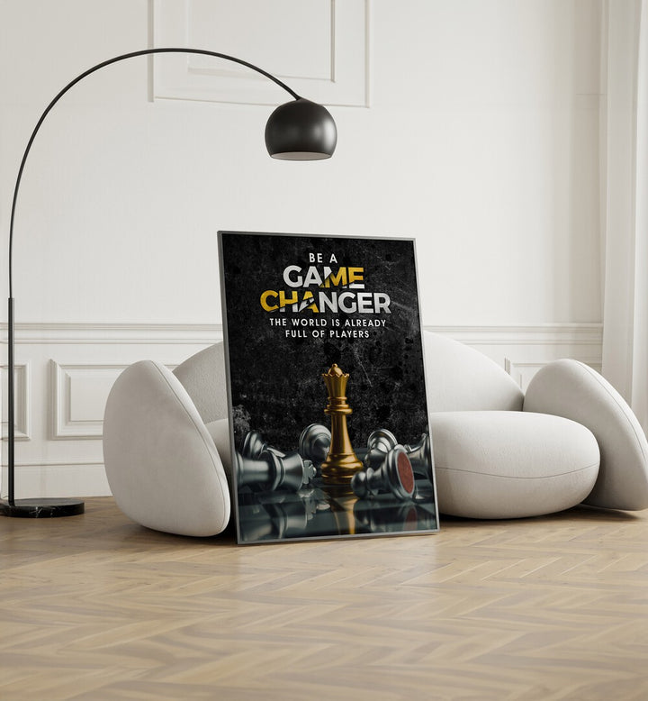 Game Changer Quotes And Typography Posters in Black Plain Frame placed on the floor near a White Sofa in the Living Room