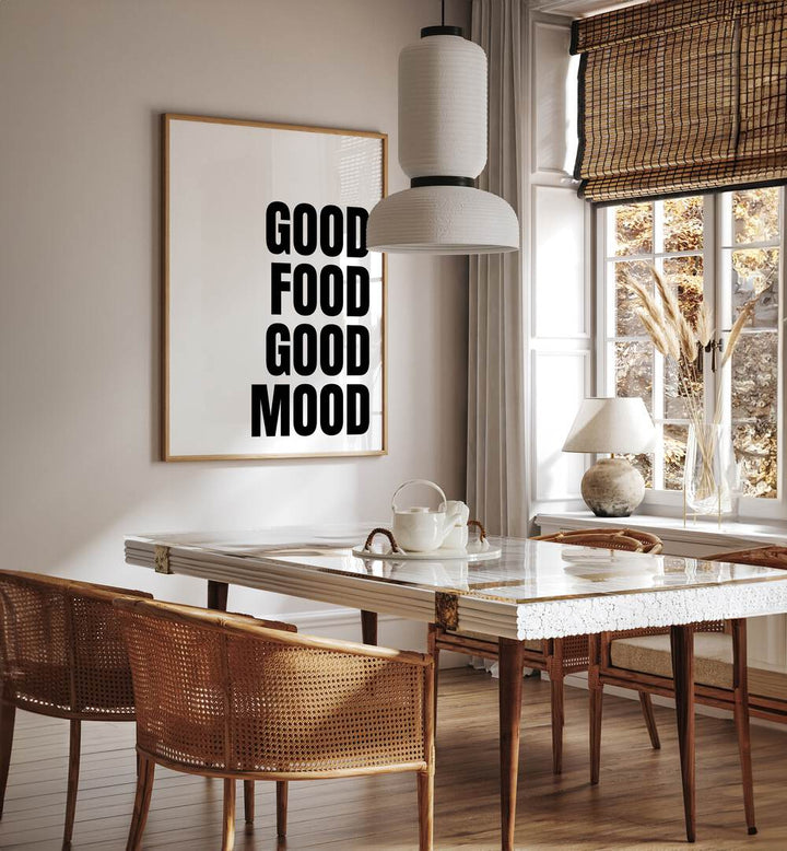 Good Food Good Mood by Athene Fritsch Quotes and Typography Posters in Oak Wood Plain Frame placed on a wall in a dining room area beside a window and behind a dining table