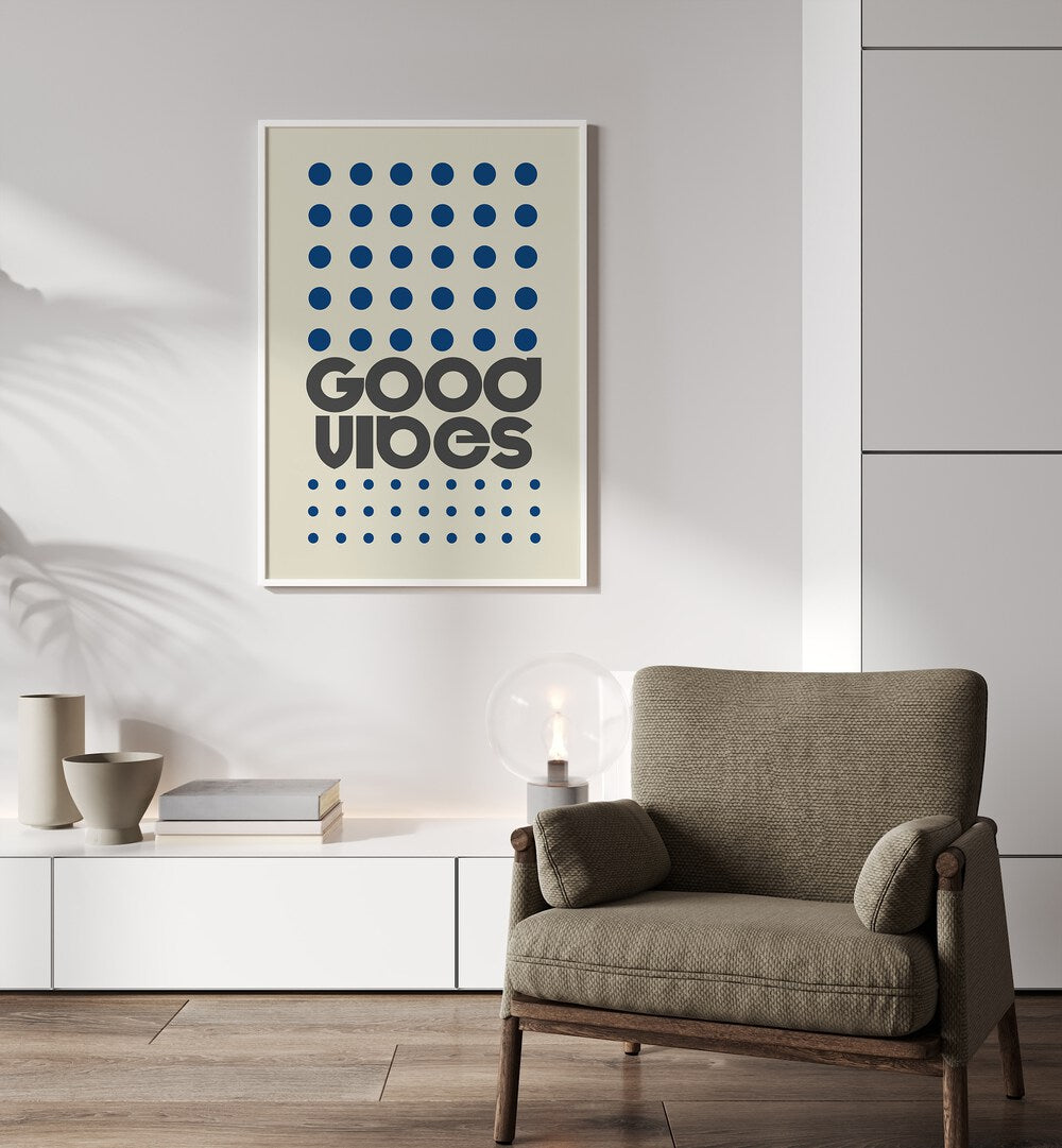 Good Vibes Quotes and Typography Posters in White Plain Frame placed on a wall behind a chair