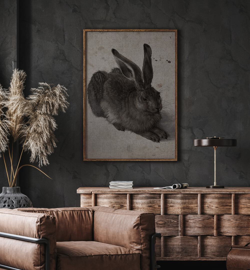 Gothic Hare Shadows In The Warren Gothic Art Prints in Oak Wood Plain Frame hanging on wall above brown chair beside plant.